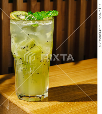 Refreshing kiwi and mint cocktail served in a tall glass on wooden table 133805187