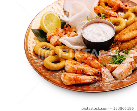 Seafood platter features shrimp, fish, and sides served on copper dish 133805196