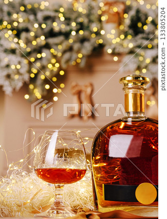 Festive whiskey glass and bottle with twinkling lights and holiday decor Festive whiskey glass and bottle with twinkling lights and holiday decor 133805204