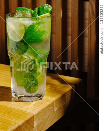 Refreshing mojito with mint and lime on wooden table in cozy setting Refreshing mojito with mint and lime on wooden table in cozy setting 133805252