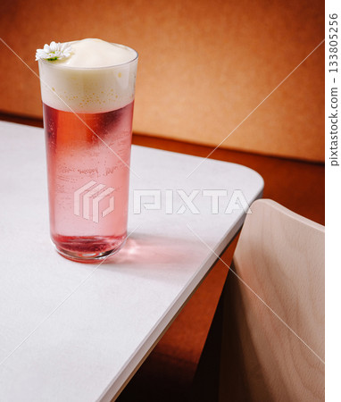 Refreshing pink drink with foam and a flower on a white table Refreshing pink drink with foam and a flower on a white table 133805256