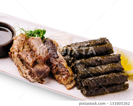 Delicious grilled meat and wrapped vine leaves served on a white plate 133805262