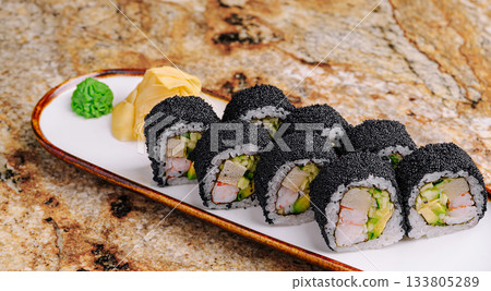 Delicious sushi rolls topped with black caviar on a smooth plate 133805289