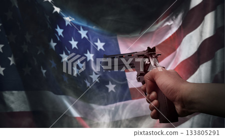 Human hand holding a revolver handgun in front of a USA flag background. Concept of gun violence 133805291