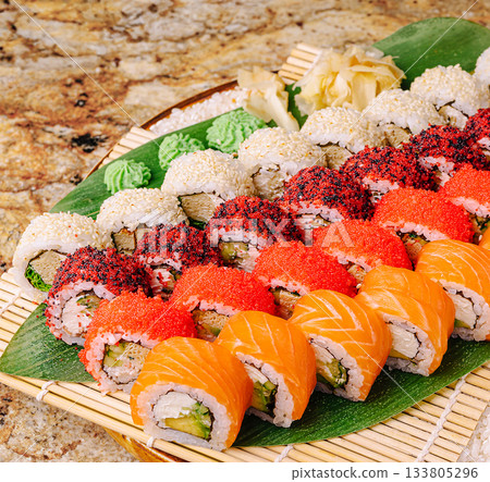 Sushi platter filled with colorful rolls displayed on a bamboo mat 133805296