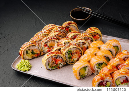 Delicious sushi rolls displayed on a plate with dipping sauce and wasabi Delicious sushi rolls displayed on a plate with dipping sauce and wasabi 133805320