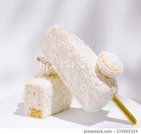 White coconut dessert displayed with a golden stick in bright light 133805324