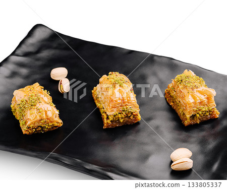 Freshly made baklava served on a sleek black plate with pistachios 133805337