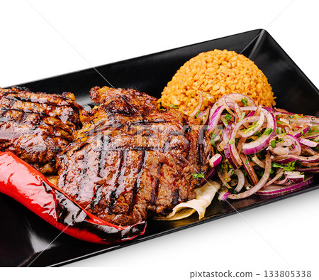 Grilled steak with rice, onions, and chili served on a black plate Grilled steak with rice, onions, and chili served on a black plate 133805338