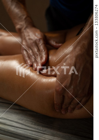 Close-up of a professional therapist performing an anti-cellulite leg massage using oil, applying firm pressure to improve blood circulation, tone the skin, and reduce cellulite in a spa environment. Close-up of a professional therapist performing an anti-cellulite leg massage using oil, applying firm pressure to improve blood circulation, tone the skin, and reduce cellulite in a spa environment. 133806274