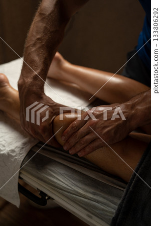 Close-up of a professional therapist giving a leg massage in a spa, applying oil and pressure with hands to relax muscles, improve circulation, and promote wellness in a calm environment. Close-up of a professional therapist giving a leg massage in a spa, applying oil and pressure with hands to relax muscles, improve circulation, and promote wellness in a calm environment. 133806292