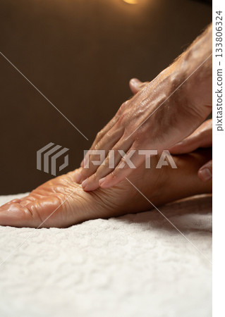 Close-up of a foot massage in a spa, therapist gently massaging the heel with oil, relaxation and wellness concept, warm light atmosphere, skin care and body therapy. Close-up of a foot massage in a spa, therapist gently massaging the heel with oil, relaxation and wellness concept, warm light atmosphere, skin care and body therapy. 133806324