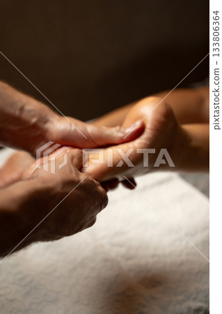Close-up of a professional foot massage session in a spa, therapist gently pressing the sole with hands, promoting relaxation, circulation, and wellness in a calm environment. 133806364