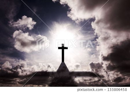 Silhouetted cross is glowing above roof peak with sun halo against swirling clouds in flat design 133806458