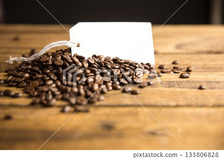 3D render showing mound of roasted coffee beans on rustic table with blank tag, white string 133806828