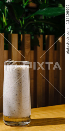 Refreshing beverage in a glass on a wooden table surrounded by greenery Refreshing beverage in a glass on a wooden table surrounded by greenery 133806962