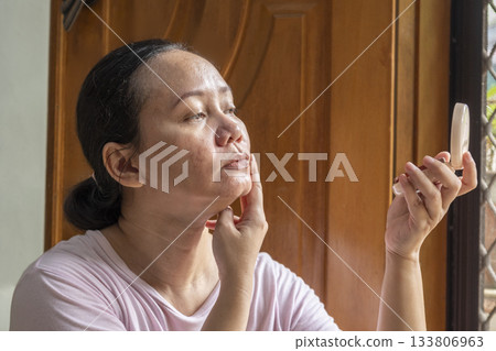 Woman is looking at herself in a mirror 133806963