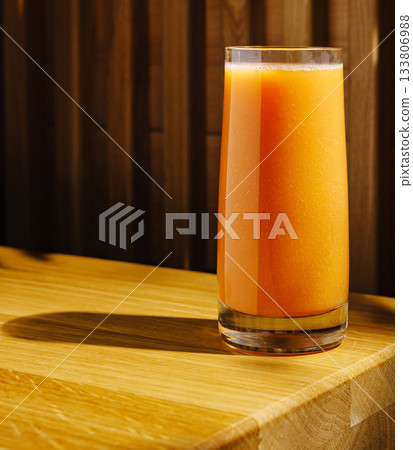 Freshly squeezed orange juice served in a tall glass on a wooden table Freshly squeezed orange juice served in a tall glass on a wooden table 133806988