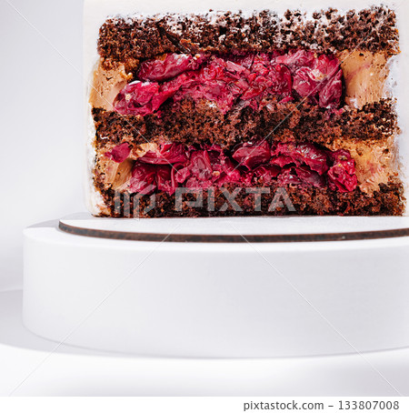 Delicious cake layers with chocolate and cherries on a round display stand Delicious cake layers with chocolate and cherries on a round display stand 133807008
