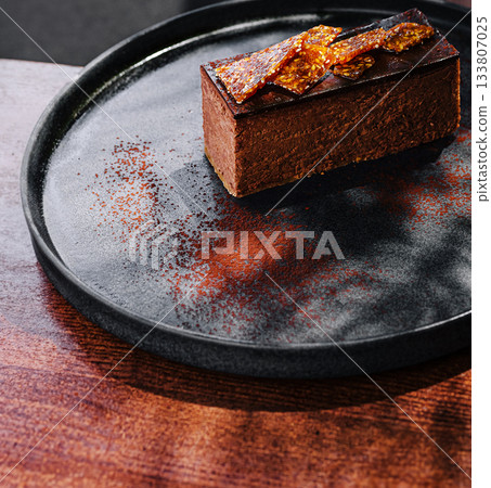 Delicious chocolate dessert with caramel topping on dark plate Delicious chocolate dessert with caramel topping on dark plate 133807025