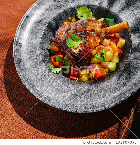 Deliciously cooked lamb shank served with fresh vegetable medley 133807055