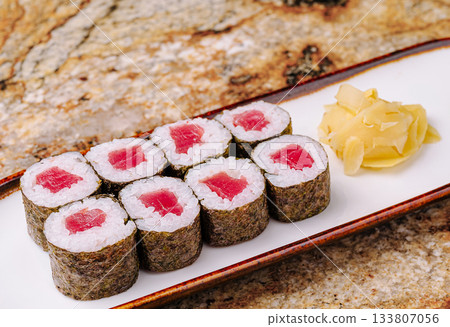 Fresh sushi rolls with tuna and pickled ginger on a wooden platter Fresh sushi rolls with tuna and pickled ginger on a wooden platter 133807056
