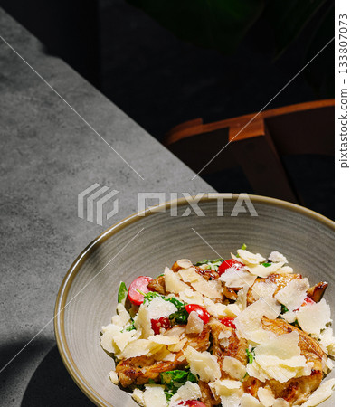 Fresh salad with radish and cheese served at a sunny outdoor table 133807073