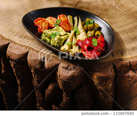 Colorful plate of grilled vegetables and pesto on wooden table Colorful plate of grilled vegetables and pesto on wooden table 133807089