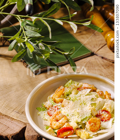 Fresh shrimp salad on a wooden table with green plants and culinary tools 133807090