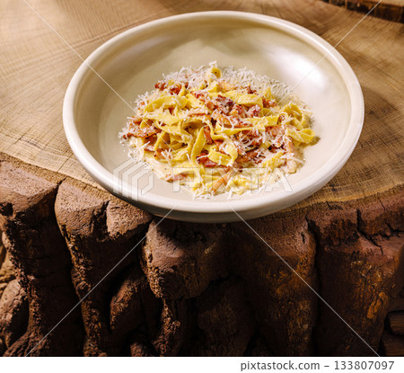 Delicious pasta dish served on a rustic wooden table in a cozy setting 133807097