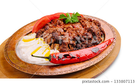 Spicy meat dish served on a traditional plate with yogurt and chili peppers Spicy meat dish served on a traditional plate with yogurt and chili peppers 133807113