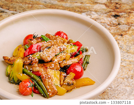 Colorful stir-fry with vegetables and chicken served on a stone countertop Colorful stir-fry with vegetables and chicken served on a stone countertop 133807118