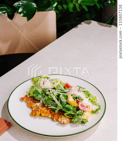 Fresh salad and grilled fish served on a white plate in a restaurant setting Fresh salad and grilled fish served on a white plate in a restaurant setting 133807138