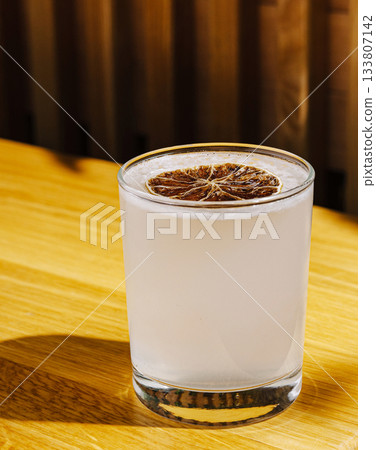Refreshing cocktail with dried lime on wooden table in cozy setting 133807142