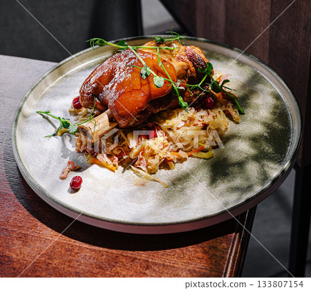 Savory pork knuckle served with cabbage on a decorative plate 133807154
