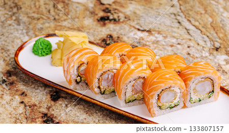 Sushi rolls on a white plate with ginger and wasabi on a marble table Sushi rolls on a white plate with ginger and wasabi on a marble table 133807157