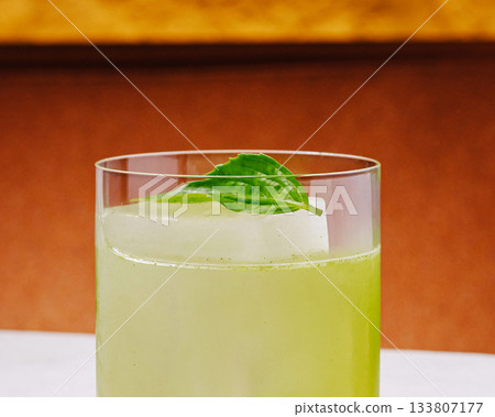 Refreshing green drink served with a basil leaf in a clear glass Refreshing green drink served with a basil leaf in a clear glass 133807177