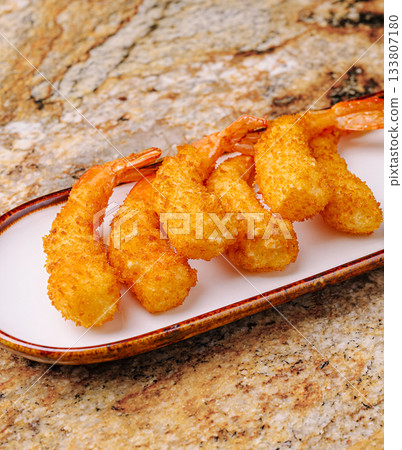Golden fried shrimp served on a white plate with a textured background Golden fried shrimp served on a white plate with a textured background 133807180