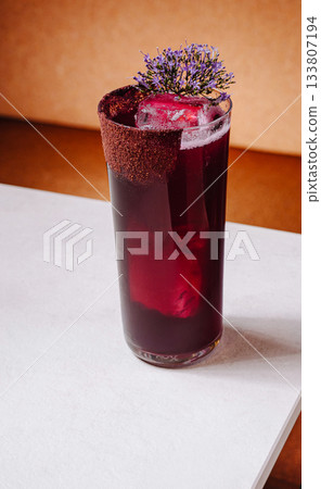 Refreshing berry drink served in a tall glass with floral garnish on table Refreshing berry drink served in a tall glass with floral garnish on table 133807194