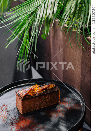 Delicious chocolate dessert with crispy topping on a black plate Delicious chocolate dessert with crispy topping on a black plate 133807204