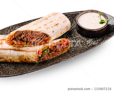 Delicious wraps with meat and fresh vegetables served with sauce on a plate Delicious wraps with meat and fresh vegetables served with sauce on a plate 133807218