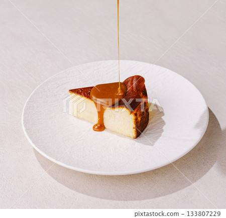 Perfectly caramel drizzled cheesecake slice on a white plate 133807229