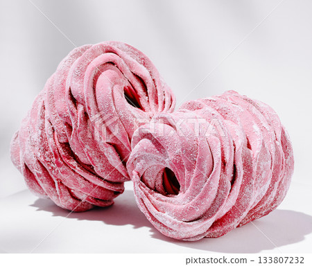Delicate pink marshmallow cones on display with a soft, elegant background Delicate pink marshmallow cones on display with a soft, elegant background 133807232