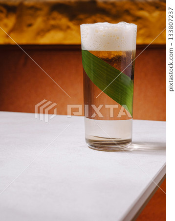 Refreshing drink served in a tall glass with a decorative leaf Refreshing drink served in a tall glass with a decorative leaf 133807237