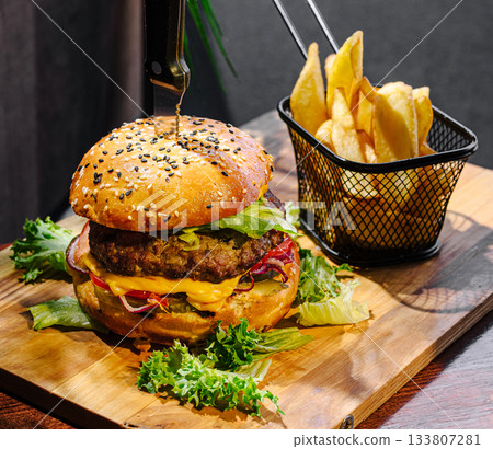 Delicious cheeseburger with crispy fries served on a wooden platter 133807281
