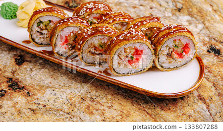 Sushi rolls arranged neatly on a decorative plate with garnishes Sushi rolls arranged neatly on a decorative plate with garnishes 133807288