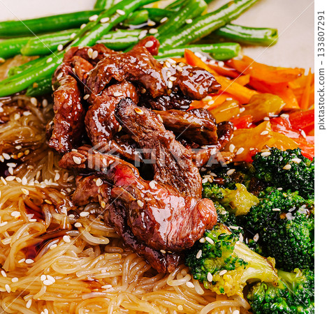 Delicious stir-fried noodles with beef and fresh vegetables served on a plate Delicious stir-fried noodles with beef and fresh vegetables served on a plate 133807291