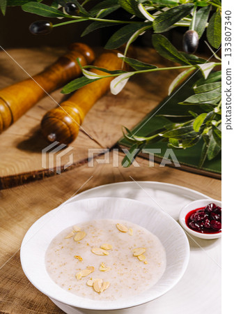 Warm bowl of oatmeal with almond slices and berry sauce on rustic table 133807340