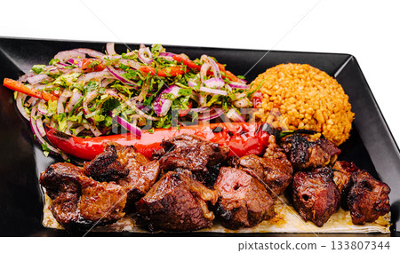 Delicious grilled meat served with rice and fresh vegetable salad Delicious grilled meat served with rice and fresh vegetable salad 133807344