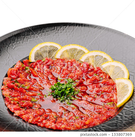 Delicious beef tartare served with fresh lemon slices and herbs Delicious beef tartare served with fresh lemon slices and herbs 133807369